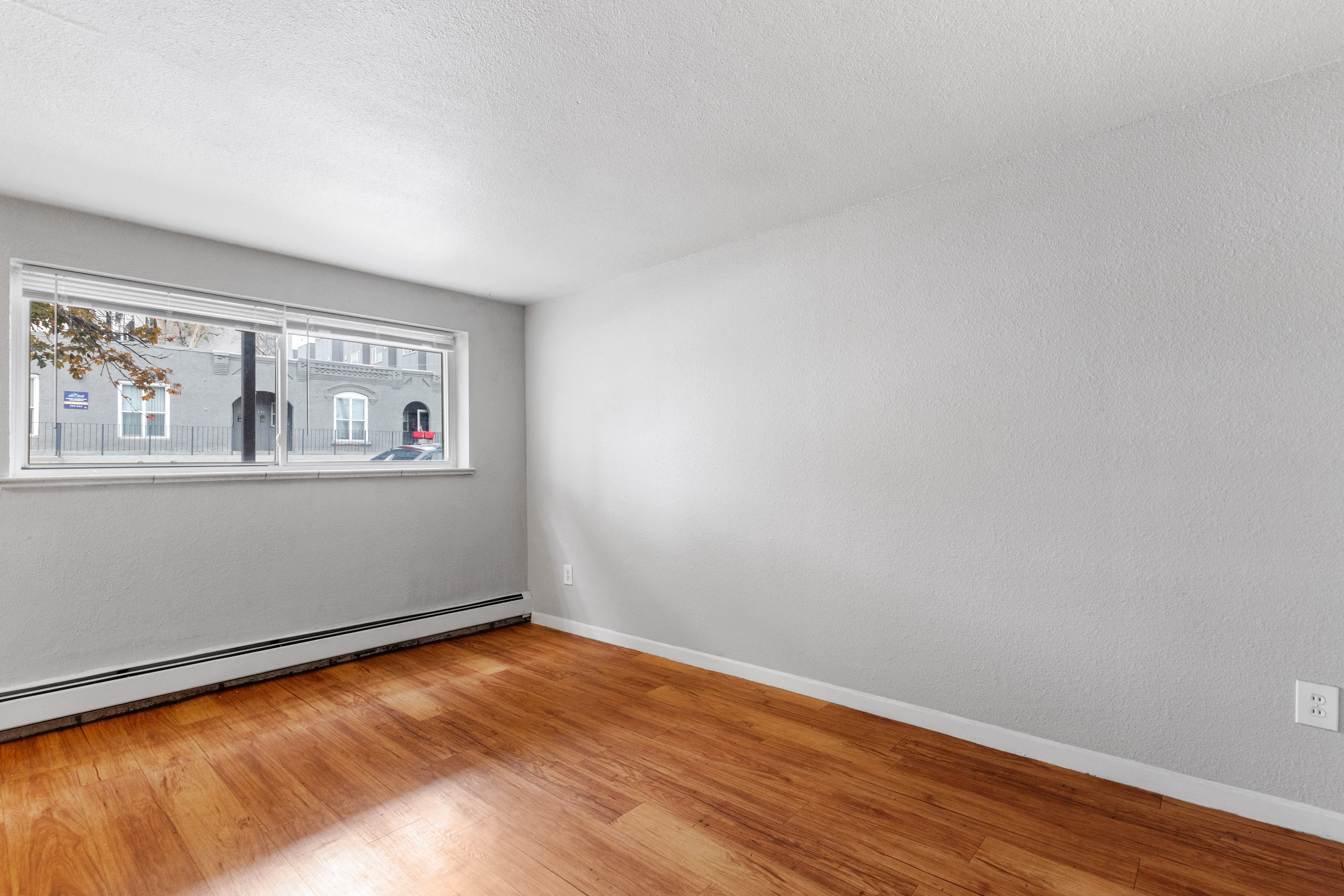 the living room of an apartment with wood floors and a window
